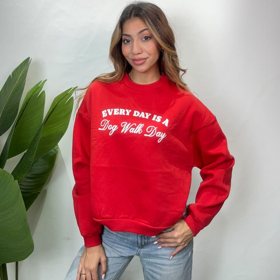 Woman in a red crew neck sweatshirt with a white Every Day Is A Dog Walk Day slogan and jeans