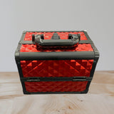 Glossy red studded aluminium case closed with black edge rails and a black carry handle