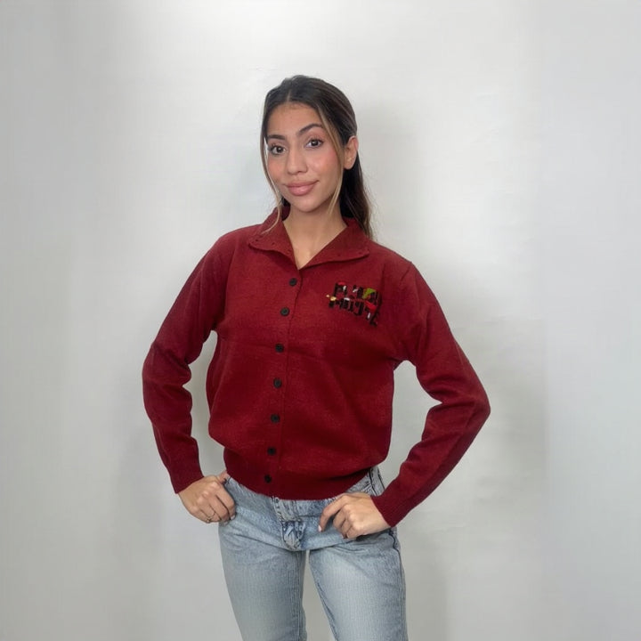 Deep red knit cardigan with black buttons and ribbed hem, hands on hips