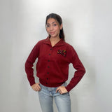 Deep red knit cardigan with black buttons and ribbed hem, hands on hips