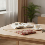 Medallion tapestry bag resting on a wooden table beside a mug