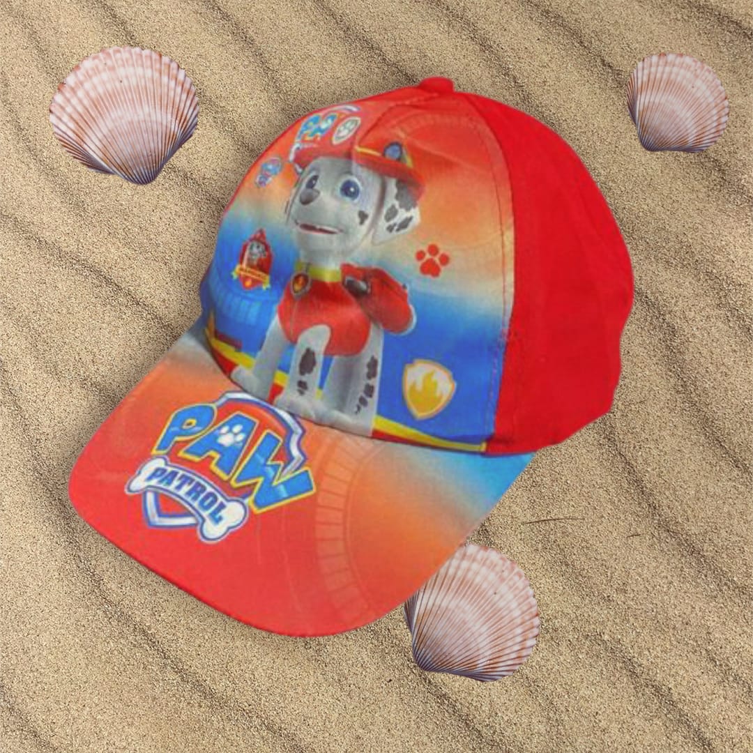 Red and blue firefighter pup cap lying on beach sand with scallop shells