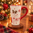 Tall white ceramic mug with a raised reindeer, red snowflakes and a glossy red handle