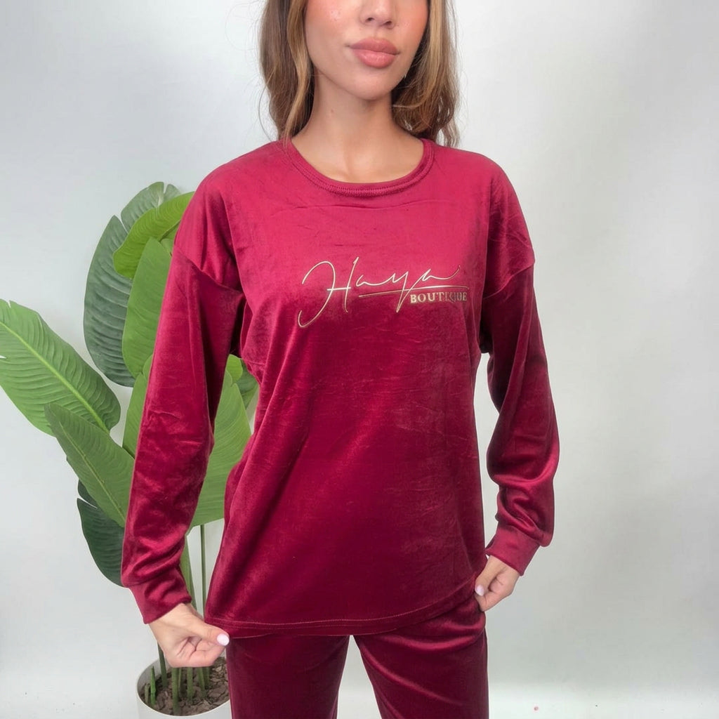 Close up of a red velvet pajama top with a gold script print on the chest