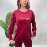 Close up of a red velvet pajama top with a gold script print on the chest