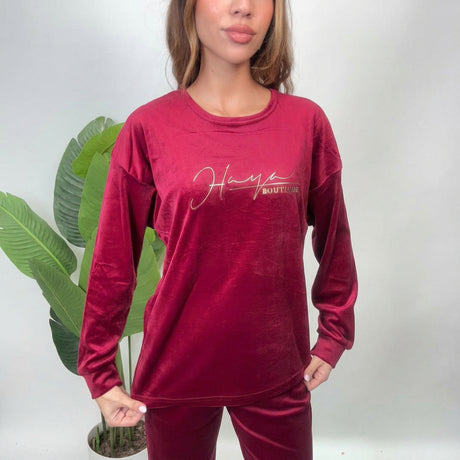 Close up of a red velvet pajama top with a gold script print on the chest