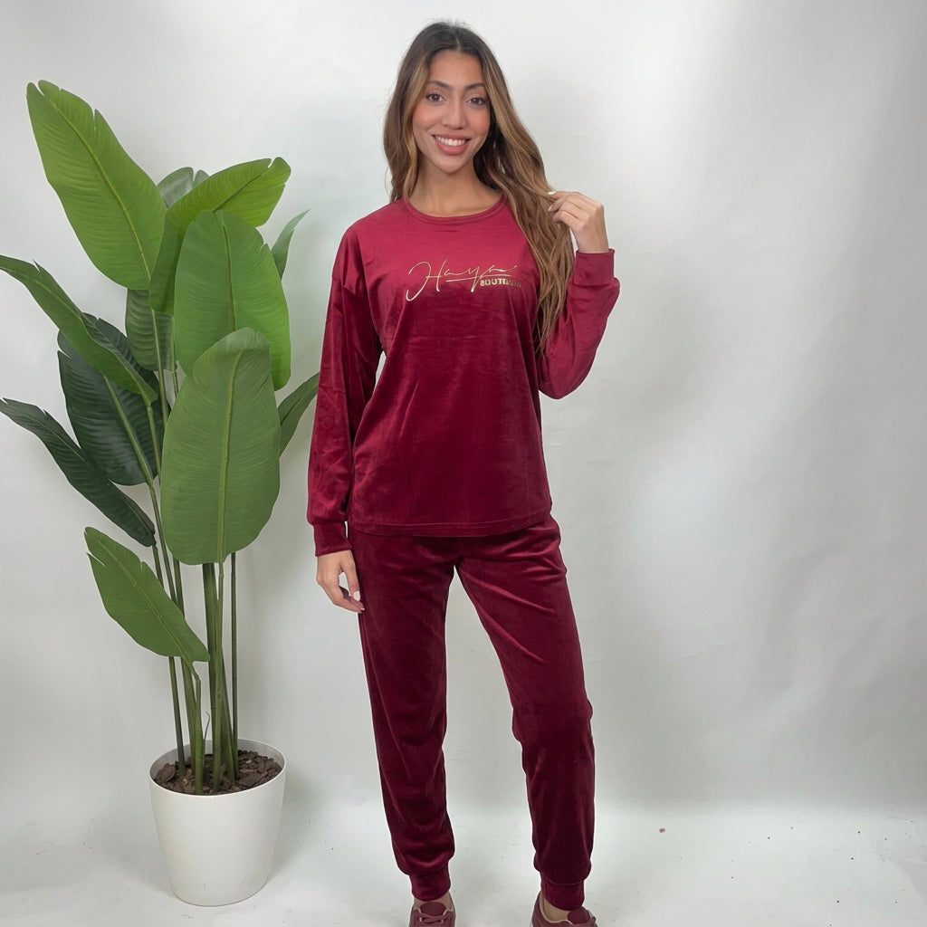 Woman in a red velvet PJ set with a gold script print top and jogger pants
