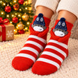 Red and white striped Christmas socks with a grey animal in a navy beanie and red plush arms
