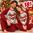 Smiling couple in matching reindeer Christmas pyjamas with red and black striped sleeves and pants by a fireplace