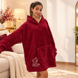 Woman in a berry red fleece hooded blanket with a white bear outline near the hem