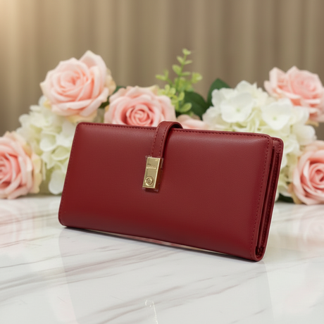 Red wallet with a gold clasp on a marble surface with flowers in the background