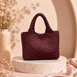 Red woven handbag on a marble stand with flowers in the background