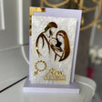 Gold line art Holy Family above the words Bless Our Family on a pearl panel