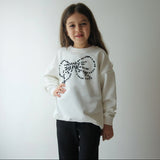 Close up of the beaded rhinestone bow on a cream sweatshirt