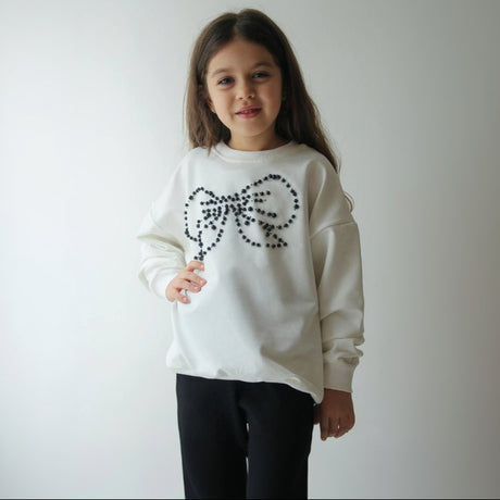 Close up of the beaded rhinestone bow on a cream sweatshirt