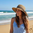 Tan floppy straw sun hat with a wide grey ribbon band, worn with a blue sundress