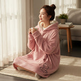 Rose pink hooded blanket with sherpa lined hood and teddy bear embroidery worn seated on a rug