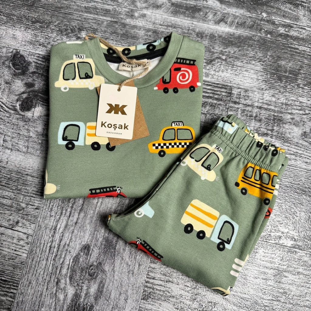 Close up of the car, bus and truck print on sage green pajama fabric