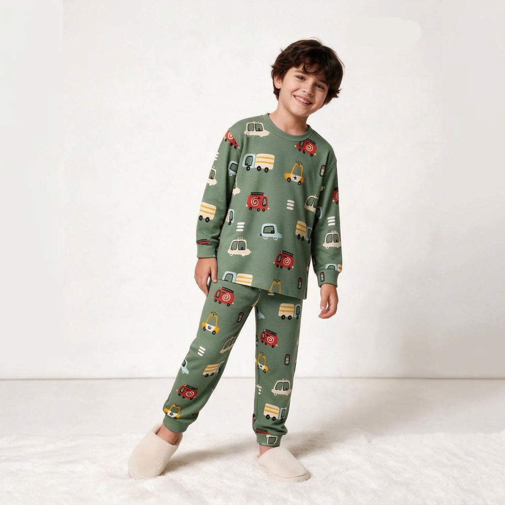 Smiling boy in a sage green long sleeve pajama set with colourful car and truck print