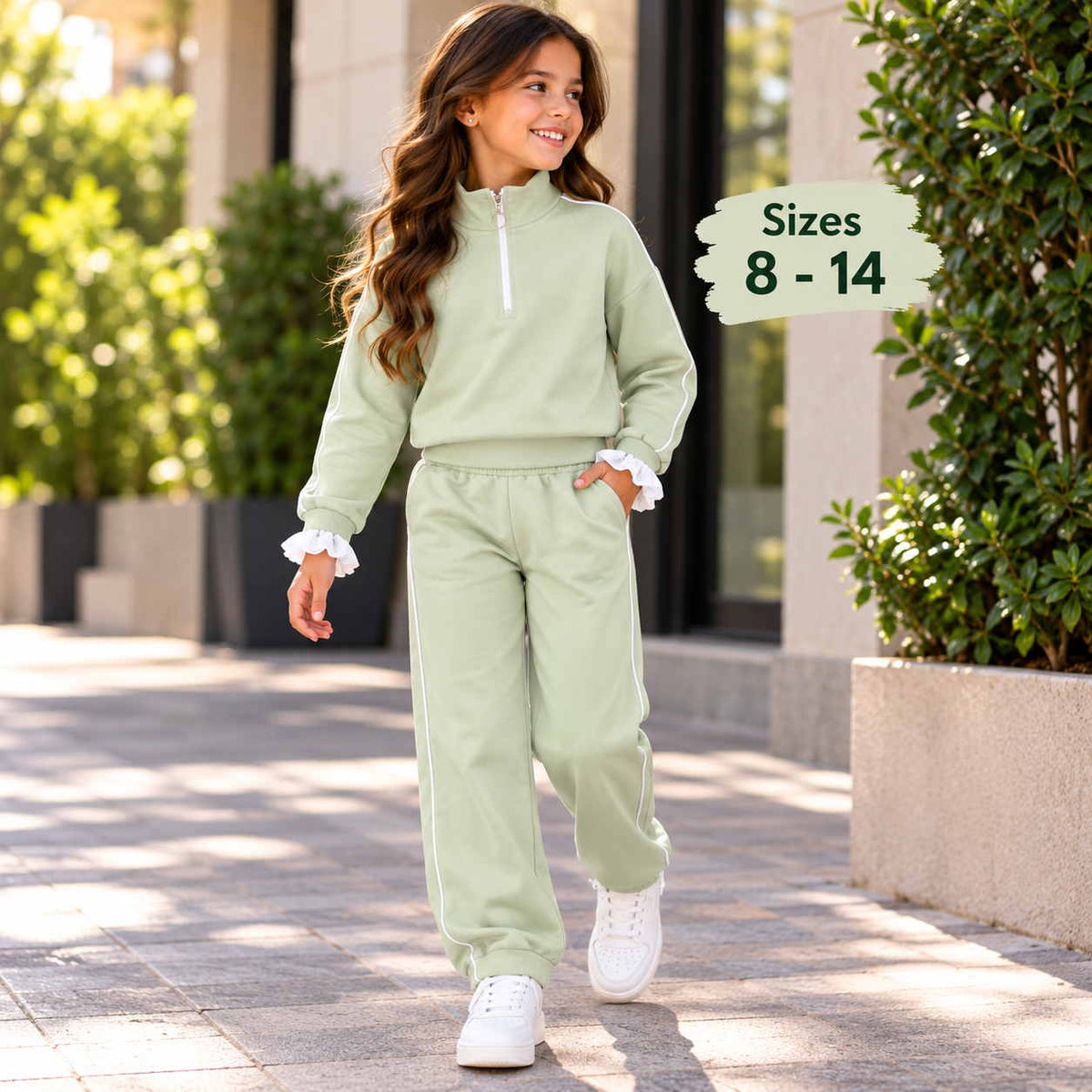 Girl walking in a sage green half zip jogging set with white piping, ruffle cuffs and white sneakers
