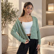 Sage green lace knit cardigan worn open over a white cami with black trousers