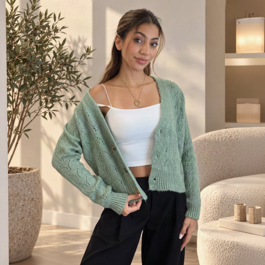 Sage green lace knit cardigan worn open over a white cami with black trousers