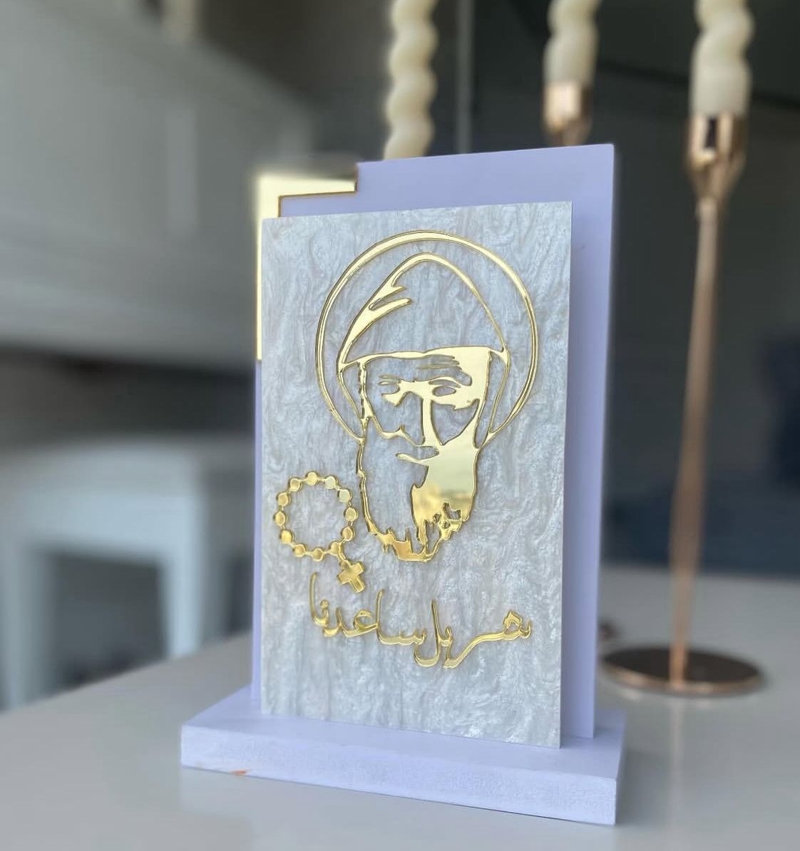Hooded bearded saint in gold outline with a halo, Arabic script and a small rosary