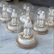 Full length standing monk holding an open book under an unribboned glass dome