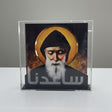 The hooded saint painted against burnt amber above a black base with etched Arabic