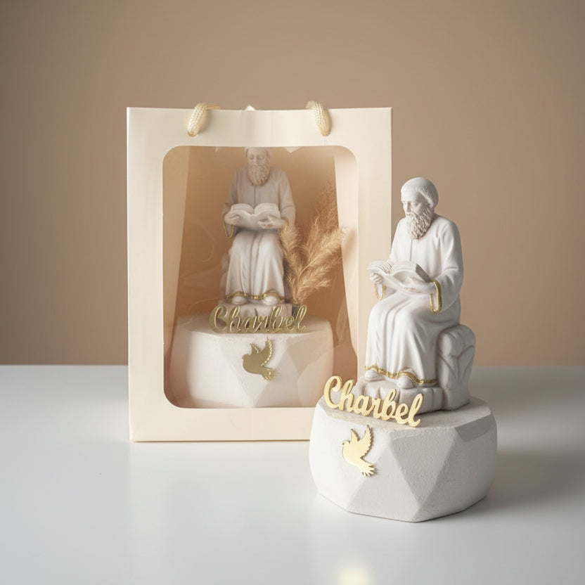 Seated monk statue reading a book beside a cream gift bag holding a second one