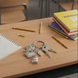 School supplies keychain with calculator, notebook, and backpack charms on a desk