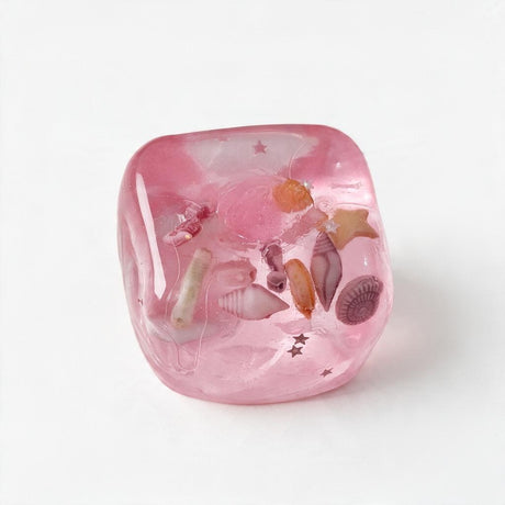 Pink jelly cube squishy with tiny shells, a starfish and silver stars inside