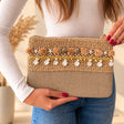 Beige crochet clutch bag with starfish, pom poms and a row of hanging white shells