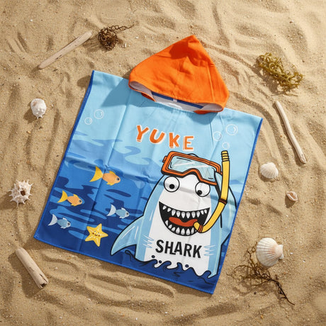 Blue shark poncho towel with an orange hood and snorkelling shark print flat lay on sand