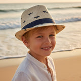 Young boy in a natural beige straw fedora sun hat covered in small navy shark silhouettes