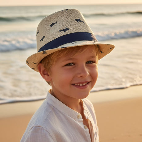 Young boy in a natural beige straw fedora sun hat covered in small navy shark silhouettes