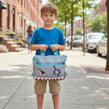 Boy on a pavement holding a grey shark tablet bag with red teeth and blue trim