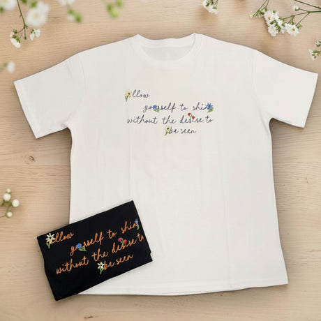 White tshirt with printed text on a wooden surface with flowers