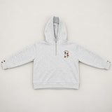 Flat lay of a grey marl hoodie with a quarter zip and small embroidered chest patch