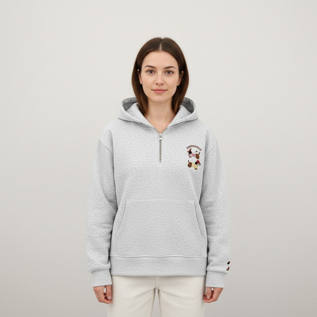 Woman facing the camera in a heather grey half zip hoodie with cream trousers