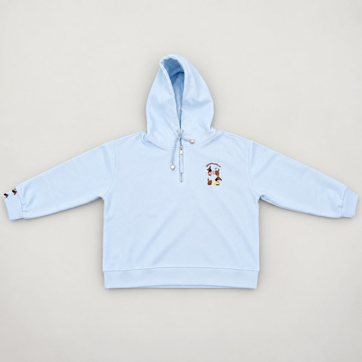 Baby blue hooded sweatshirt laid flat, showing drawcords and the pups embroidery