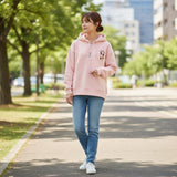 Full outfit of a pink hooded top, straight jeans and white trainers on a city street