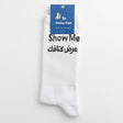 White crew socks knitted with Show Me above a line of black Arabic lettering