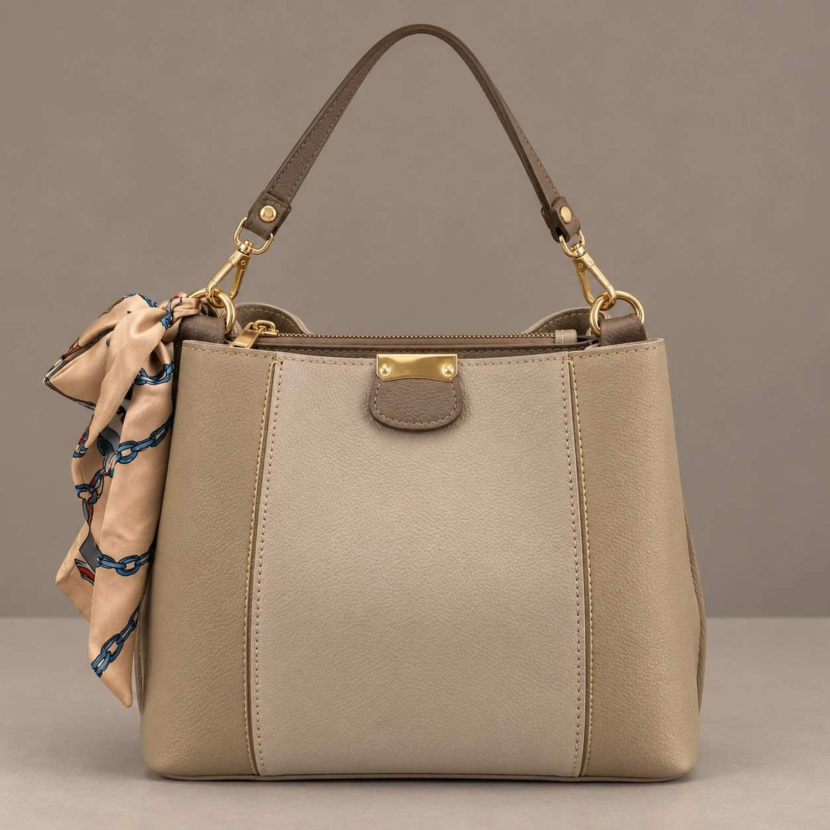 Two tone beige and taupe top handle bag with gold clips and a peach and teal scarf