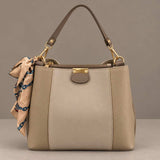 Two tone beige and taupe top handle bag with gold clips and a peach and teal scarf