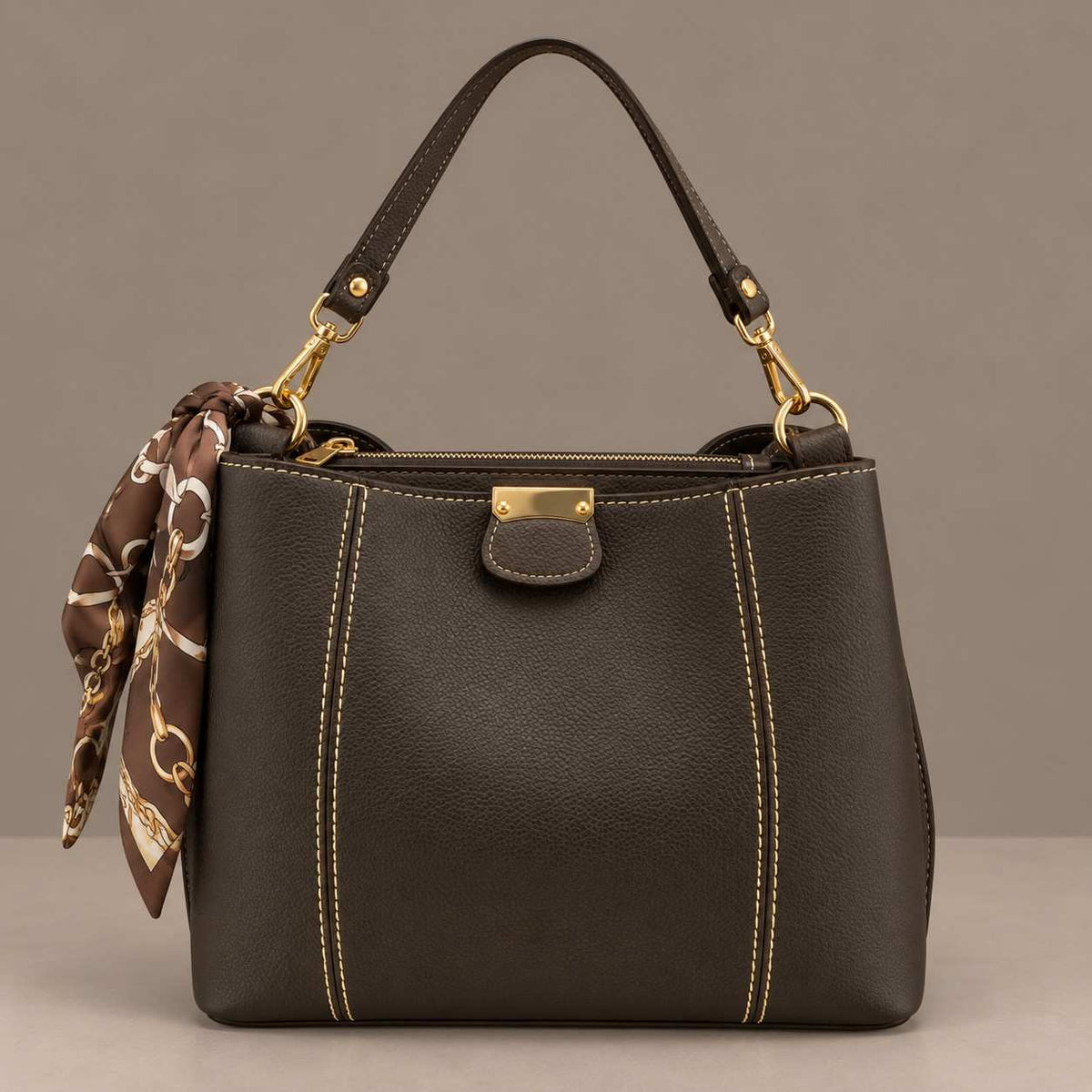 Dark brown top handle bag with contrast stitching and a brown chain print scarf