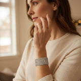 Woman wearing a silver bracelet, sitting indoors with a blurred background