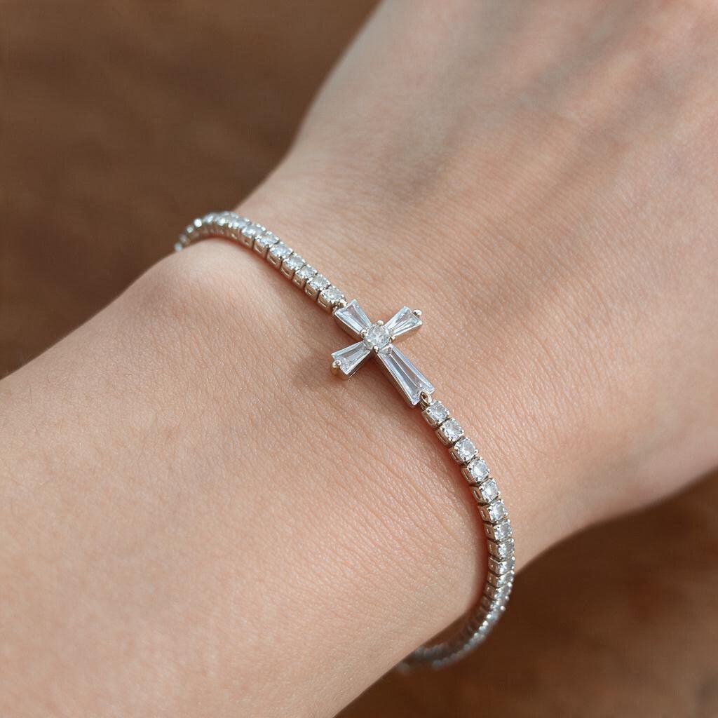 Silver tennis bracelet with a baguette crystal cross worn on the wrist in soft daylight