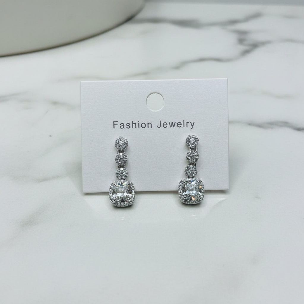 Silver earrings on a 'Fashion Jewelry' card with a marble background