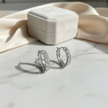 Silver crystal hoop earrings on a marble surface